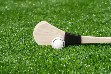 Hurling bat and sloitar on green grass. Horizontal sport theme poster, greeting cards, headers, website and app - obrazy, fototapety, plakaty