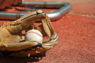 An old baseball glove and baseball lie on the lawn