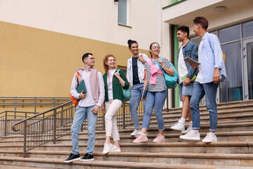 Group of happy young students walking down stairs outdoors