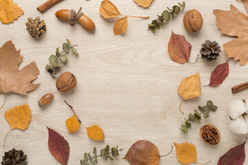 Autumn leaves with decor on wooden background, top view
