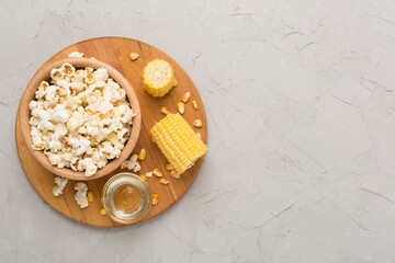 Prepared popcorn with ingredients on concrete background, top view