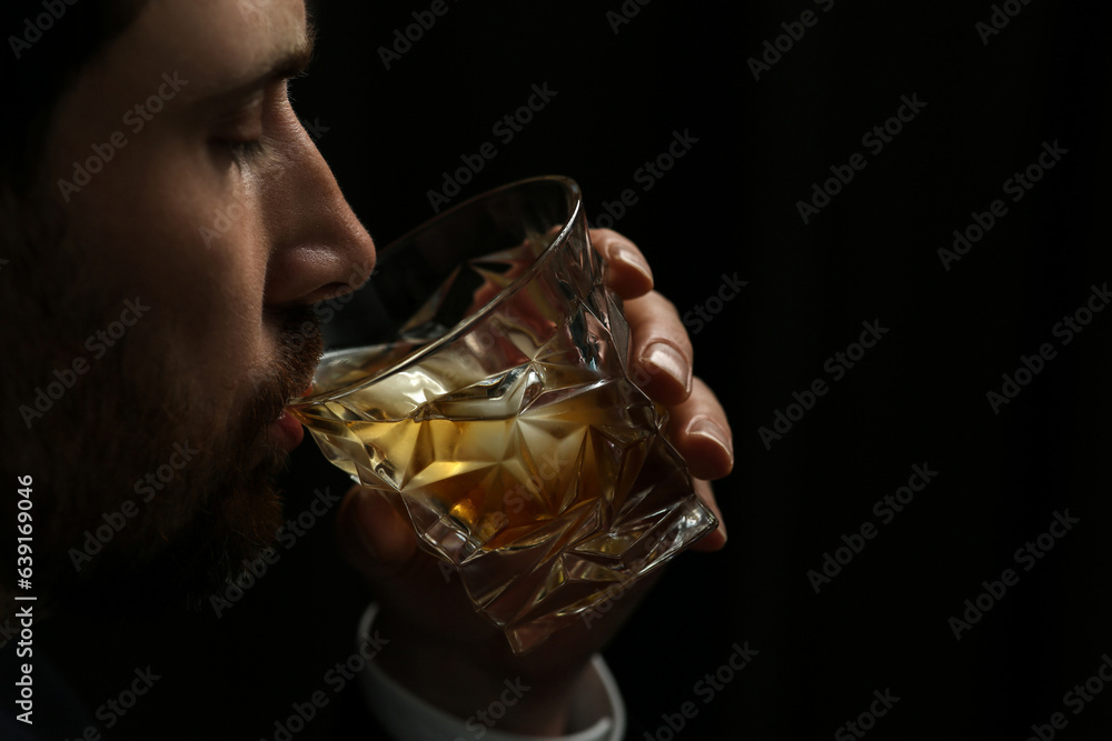 Wall mural Man drinking whiskey on black background, closeup. Space for text