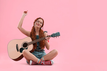Stylish young hippie woman with guitar on pink background