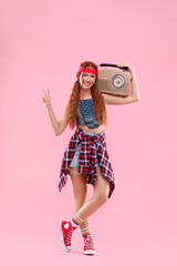 Stylish young hippie woman with radio showing V-sign on pink background
