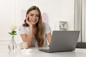 Happy woman with laptop at white table