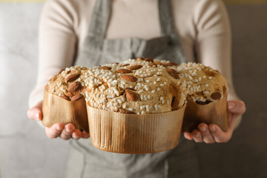 Woman with delicious Italian Easter dove cake (traditional Colomba di Pasqua) near grey wall, closeup