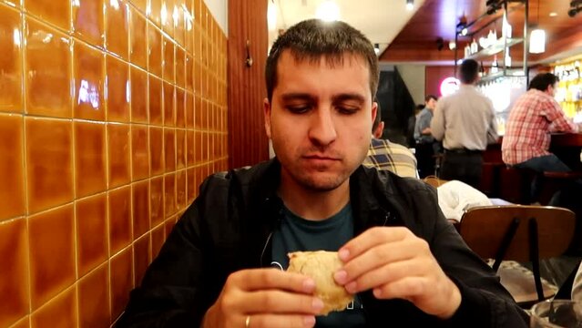 Man eating a prego for dinner at a restaurant, traditional sandwich from Porto