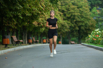 Athletic young woman in sportswear jogging in the park. Fitness and healthy lifestyle. Portrait of a beautiful young woman in sportswear outdoors. Sport fitness model caucasian ethnicity training outd