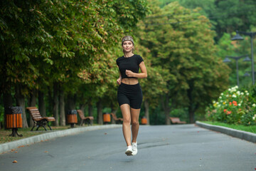 Athletic young woman in sportswear jogging in the park. Fitness and healthy lifestyle. Portrait of a beautiful young woman in sportswear outdoors. Sport fitness model caucasian ethnicity training outd