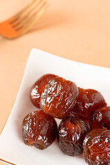 Seedless red dates in a white plate, indoor shot, clean background, closeup