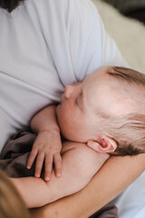 a small child is sleeping in his mother's arms. a newborn baby. mom's daughter. parenthood. childhood