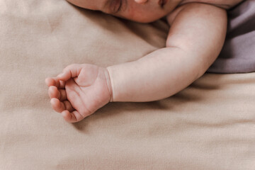 the baby is sleeping in his crib. a child's hand on a beige background
