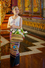 Pretty girl wearing beautiful traditional Thai dresses in Asian tradition Buddhism to make merit at...