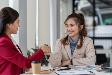 team work process Two asian businesswomen shaking hands and discussing documents project idea...