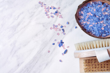 Cacao bowl with the pink mineral salt, loofah and scrub brush on marble table in spa. Healthcare...