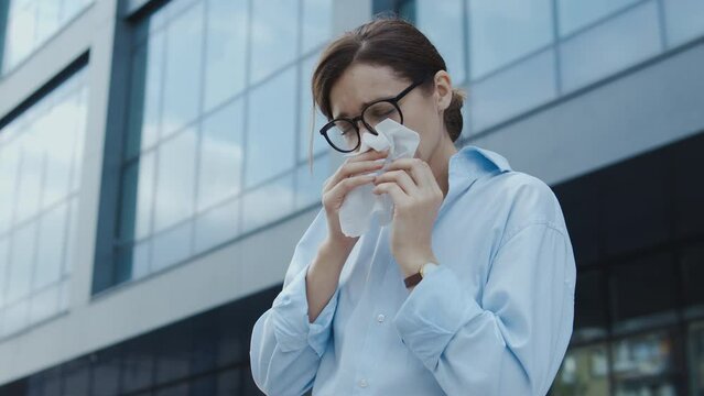 Unhealthy woman sneezing blowing her nose into paper napkin, seasonal allergy