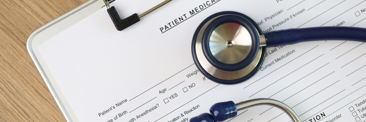 Blank sheet of patient's medical history form with stethoscope and pills, top view.