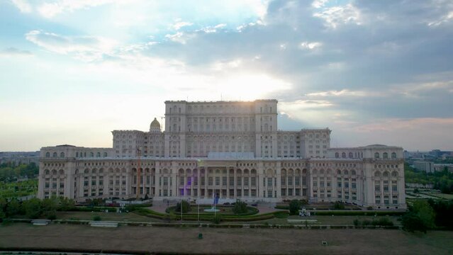 Stunning Rotating Drone View of the Palace of Parliament in Bucharest, Romania at Sunset with Sun Rays Bursting Over the Building