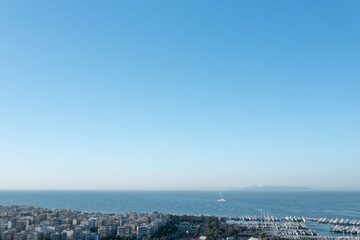 Naklejka premium Athens' Seaside Vista: Urban Houses and Lone Ship on Calm Waters