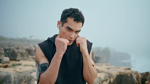 Professional athlete punching workout at seaside closeup. Strong boxer posing