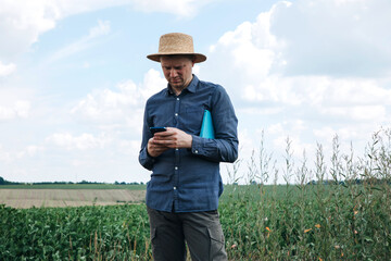 Farmer, agronomist in the soybean field. Controlling the growth of agricultural crops. Green soy with beans. Front view