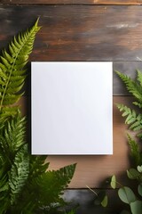 A white sheet, a blank sheet of paper, on a wooden table, a fern all around.