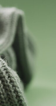 Micro vertical video of close up of green wooly knitted fabric with copy space on green background