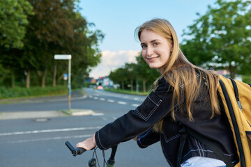 Fototapeta na wymiar Portrait of teenage student girl with backpack on bicycle