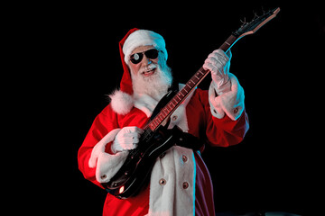 Santa Claus playing the electric guitar in a nightclub at a Christmas and New Year party or...