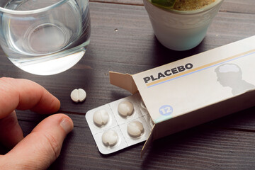 Placebo effect concept: man take a pill from a placebo box of pills - obrazy, fototapety, plakaty