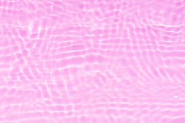 Purple water with ripples on the surface. Defocus blurred transparent pink colored clear calm water surface texture with splashes and bubbles. Water waves with shining pattern texture background.