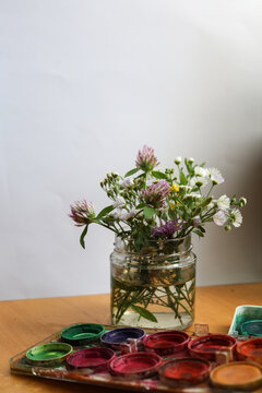 selective focus still life with wild flowers in a jar and water colors