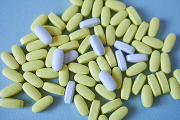 Close up of yellow and white pills on blue background. Focus on foreground.