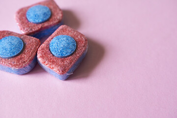 Dishwasher detergent in tablet form on pink background. 