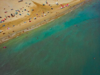 Drone photo of the sandy sea beach with people relaxing under umbrellas. Vacation and tourism...