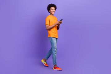 Fototapeta premium Full body size photo cadre of walking blogger guy handsome smartphone communicating while going isolated on purple color background