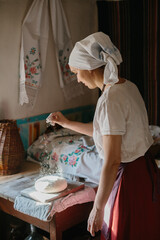 The process of traditional baking of bread at home. A woman in national Ukrainian dress bakes bread.