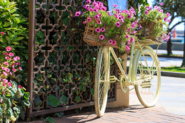 Fototapeta na wymiar a bicycle with a basket of flowers stands by the fence as a decor