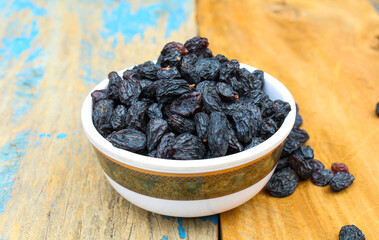 Dried Black raisins in a bowl on wooden background 