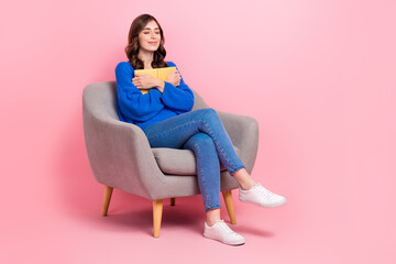 Fototapeta na wymiar Full length portrait of adorable peaceful person sit soft chair hug book closed eyes empty space isolated on pink color background