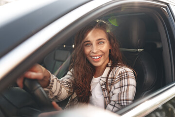 Fototapeta na wymiar Young smiling woman driving a car in the city