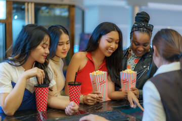 A group of multiethnic friends choosing a movie, Showtime, and movie seats at the cinema ticket...