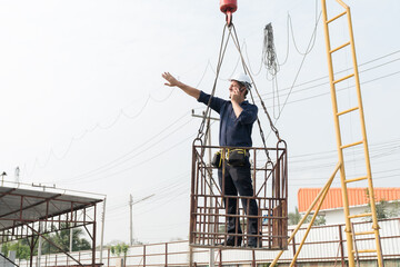 Foreman construction builder worker wearing safety uniform, helmet working on lift basket at construction site