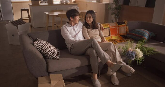 Family Home Moving in: Happy Young Korean Couple Sitting in Newly Purchased Apartment. Girlfriend and Boyfriend Moving in Together, Talking About Their Future and All the Opportunities Ahead of Them
