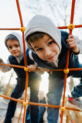 Two cute boys brothers playing on a playground outdoors