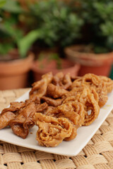 Moroccan chebakias on a white plate in a patio with plants