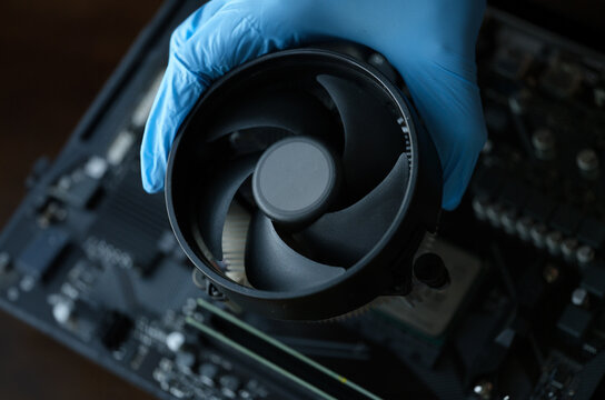 Gloved craftsman installing cooler into video card closeup. Repair and maintenance of computer equipment and electronics concept