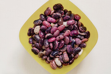 Yellow square bowl with fresh colorful scarlet runner beans on a white background.