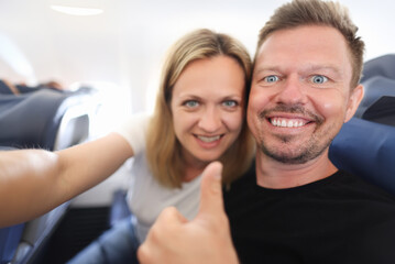 Portrait of happy young man and woman in aircraft cabin. Moving to another country for permanent...
