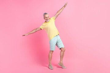 Full body size photo of carefree old retired man flying arms like wings having fun spend free time summer isolated on pink color background